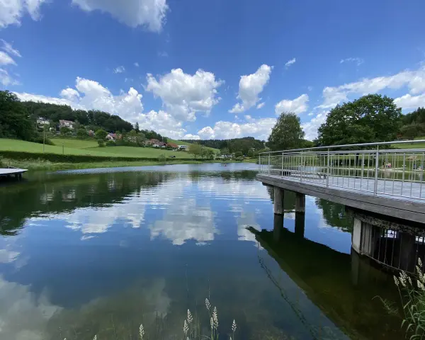 Idyllischer badesee waldhausen mit Steg und Spiegelung der Wolken im ruhigen Wasser.