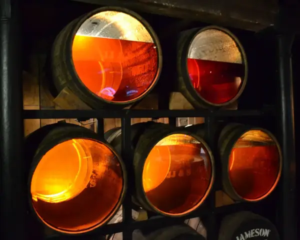 Drewniane beczki z bursztynowym whisky, część trunku to whisky angel share, dojrzewająca w ciemnej piwnicy.