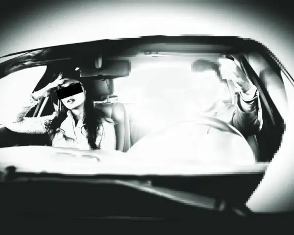 Frau im Auto, die sich die Hand ans Gesicht legt, während ein greller Blitz aufleuchtet. Ein blitzer foto, das die Szene einfängt.