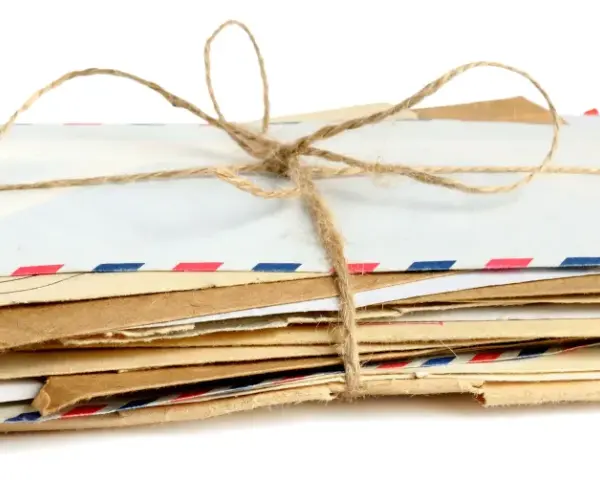 Stos listów w kopertach rozmiar C3, związany sznurkiem. Widać różne rodzaje papieru i ozdobne paski.