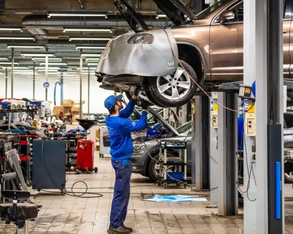 Mekaniker arbetar med en bil på en verkstad. Detta visar vad som ingår i bilservice, med verktyg och utrustning synliga.