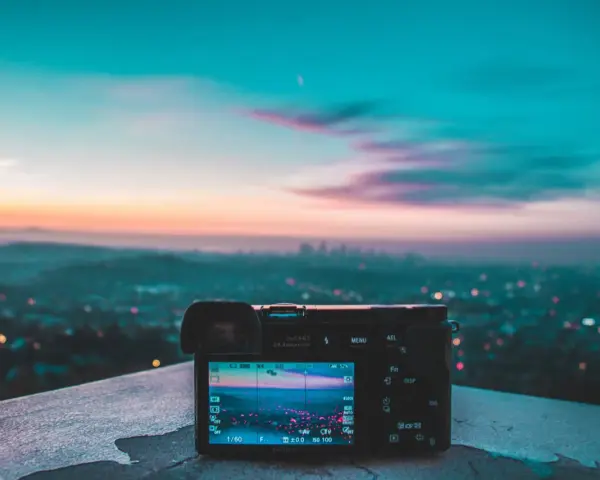 Aparat fotograficzny na tle miejskiego krajobrazu o zachodzie słońca. Piękne, kolorowe światło maluje niebo.