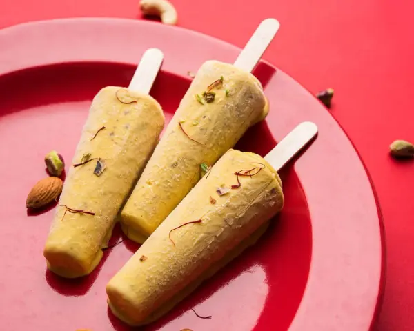Trzy pyszne kulfi na patyku, ozdobione szafranem i orzechami, idealne na letnie orzeźwienie. Ten przepis na kulfi zachwyci każdego!
