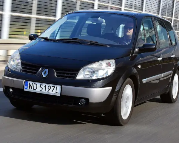 Czarny Renault Scenic 2 jedzie autostradą. Kierowca w okularach przeciwsłonecznych prowadzi auto.