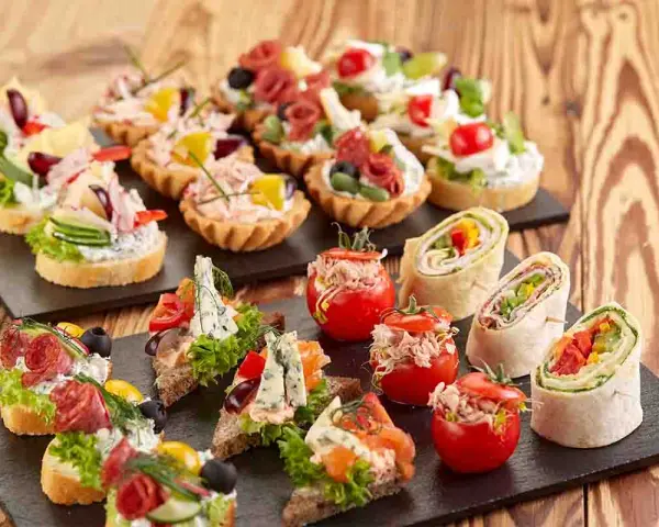 Varietà di tartine, involtini e pomodorini ripieni, perfette per idee aperitivo economico e gustoso.