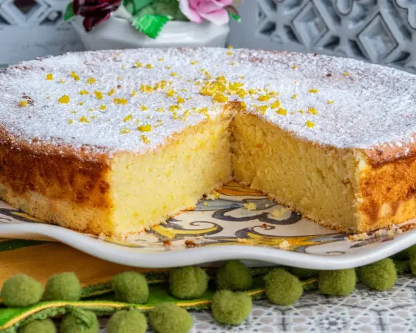 Un moelleux au citron, saupoudré de sucre glace et de zestes, attend d'être dégusté. Sa texture aérienne promet un délice.