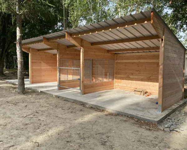 Nouveau box chevaux fait maison en bois, avec toit métallique et barrières en métal. Prêt à accueillir vos compagnons.
