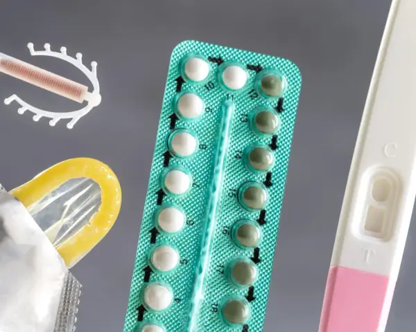 Różne rodzaje tabletek antykoncepcyjnych, wkładka domaciczna, prezerwatywa i test ciążowy.