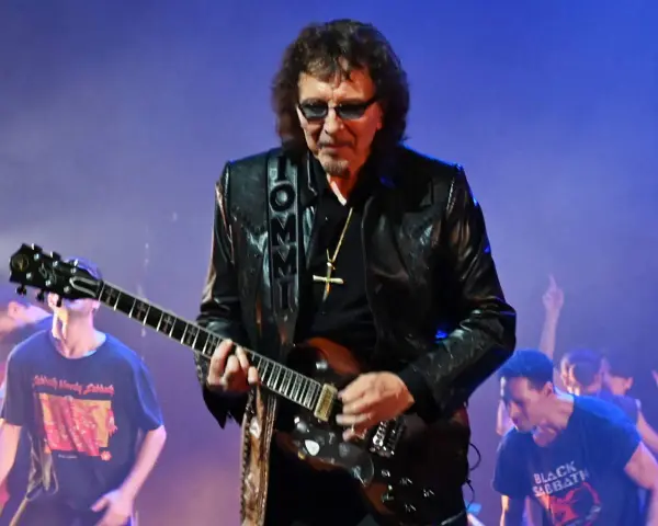 Tony Iommi, Gitarrist von Black Sabbath, spielt auf der Bühne. Im Hintergrund jubelt das Publikum.