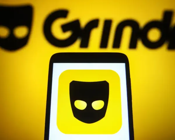 Ikona aplikacji Grindr na ekranie telefonu, na tle logo Grindr.