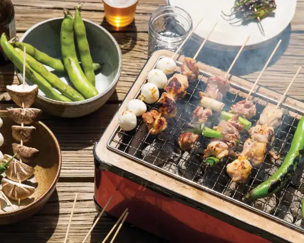 Grillowane **yakitori** z kurczakiem i warzywami, obok miska fasolki i grzybów na patyczkach.