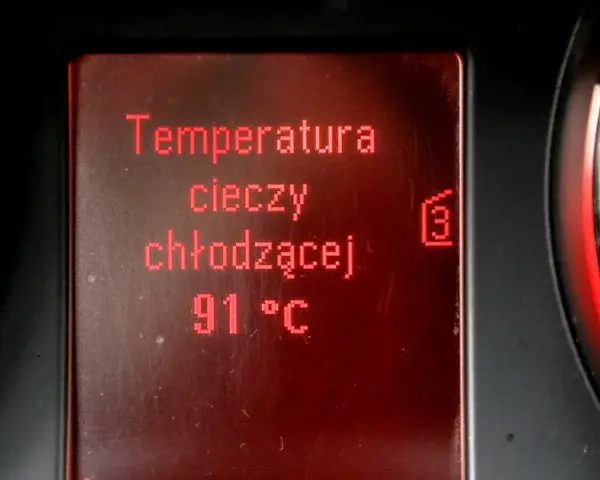 Wyświetlacz pokazuje temperaturę płynu chłodniczego: 91°C. Obok widać fragmenty wskaźników.