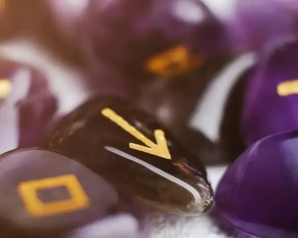 Kamienie z runami, w tym symbol przypominający numerologiczną 1, tworzą mistyczną kompozycję.