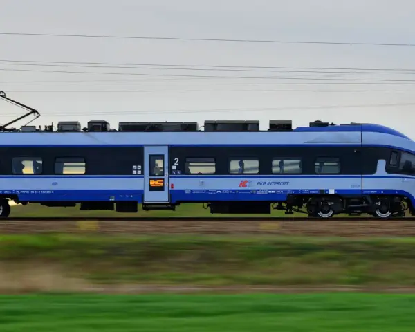 Pociąg PKP Intercity w ruchu, z widocznymi oknami i logo przewoźnika.