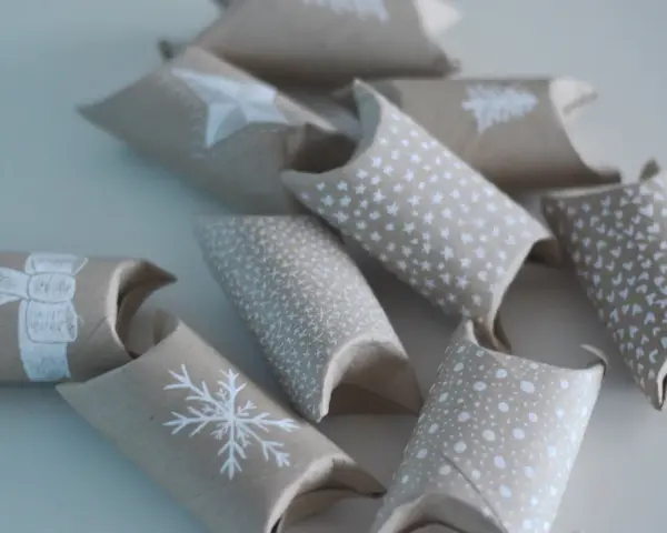 En adventskalender av toarullar, dekorerade med vita julmotiv som snöflingor och stjärnor. Perfekt för att skapa egna små överraskningar.