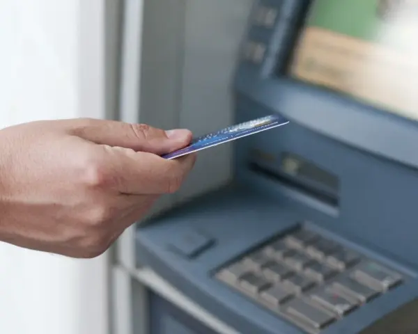Dłoń z kartą zbliża się do bankomatu. Może to być związane z obsługą konta w Credit Agricole, a nie z zajęciami komorniczymi.