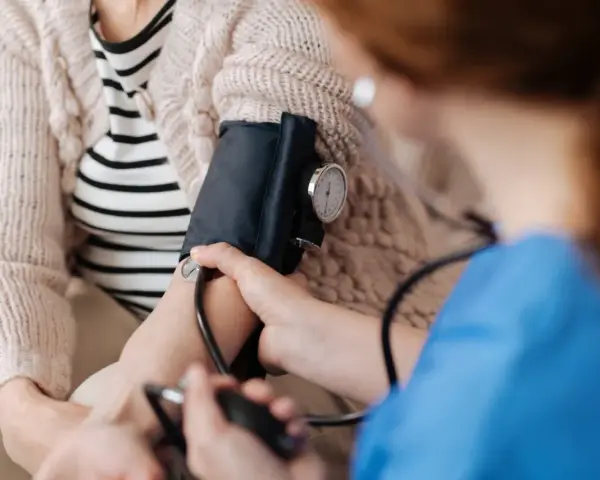 Pielęgniarka mierzy ciśnienie kobiecie w ciąży. Monitorowanie podwyższonego ciśnienia pod koniec ciąży jest kluczowe dla zdrowia mamy i dziecka.