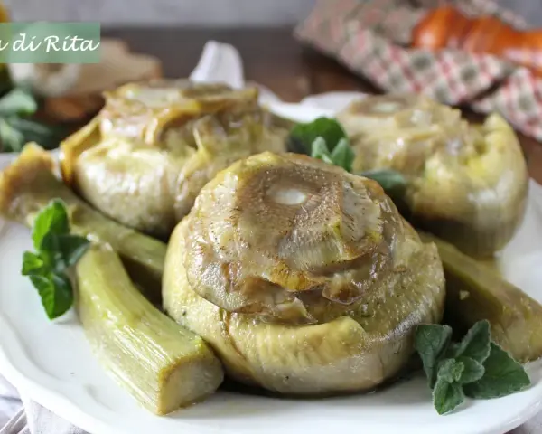 Carciofi alla romana cotti a puntino, teneri e saporiti, guarniti con menta fresca su un piatto bianco.