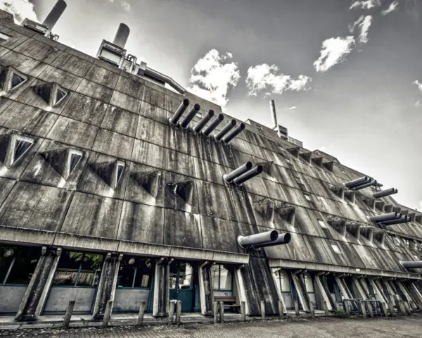 Betonriese im **Brutalismus Berlin**: Eine Fassade mit dreieckigen Fenstern und Rohren, die wie Kanonen aussehen.