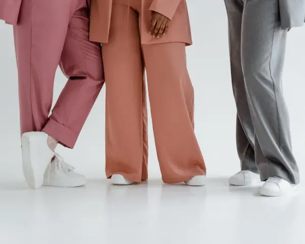 Trzy osoby w eleganckich stylizacjach. Jedna w różowych spodniach, druga w brzoskwiniowych, a trzecia w szarych. Zastanawiasz się, jaka marynarka do szarych spodni pasuje najlepiej?