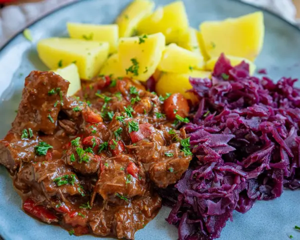 Herzhaftes Gulasch mit Kartoffeln und Rotkohl, ein klassisches Gulasch Rezept, das Leib und Seele wärmt.