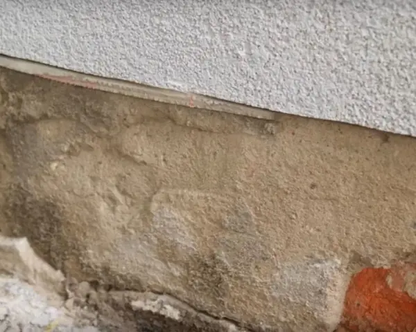 Fragment ściany z widoczną warstwą izolacji i miejscem na iniekcję.
