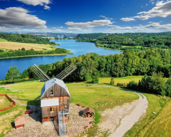 Wiatrak na tle jeziora i lasów. Tak właśnie wyglądają Kaszuby, malowniczy region pełen zieleni i wody.