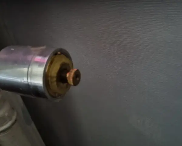 En gammal AGA termostat på ett element. Den kromade delen har en mässingsfärgad ratt.