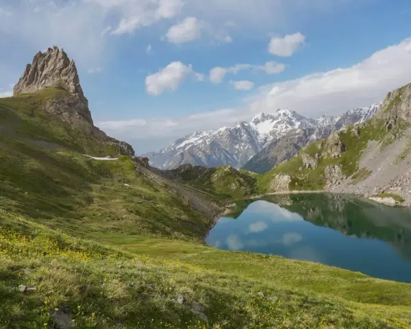 Magnifique lac alpin reflétant les montagnes enneigées, idéal pour une randonnée près de Briançon.