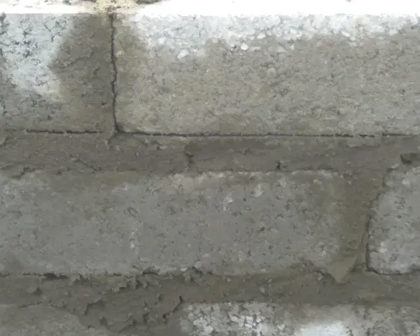 Widok z bliska na ścianę z bloczków betonowych, pokazujący grubość spoiny między nimi.