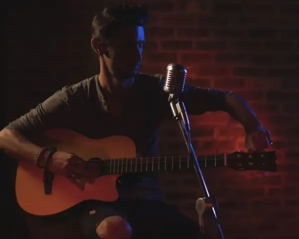 Mann stimmt seine Gitarre, bereit für die Aufnahme. Die Gitarren-Tunings sind entscheidend für den perfekten Klang.