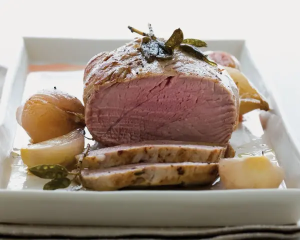 Succulento filetto al forno, cotto alla perfezione con cipolle e erbe aromatiche, servito su un piatto bianco.