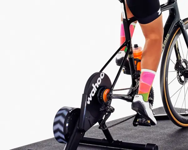 Cyclist training indoors on a bike with a Wahoo trainer, experiencing adjustable bike resistance for a challenging workout.