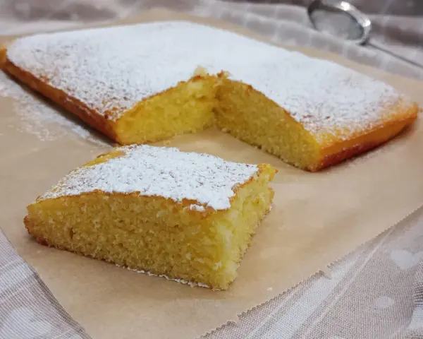 Ein saftiger Kuchen, bestäubt mit Puderzucker, ideal für glutenfreie rezepte mit reismehl.
