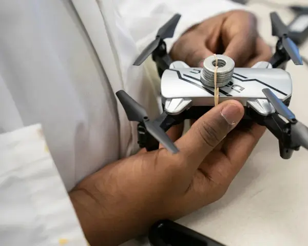 A person holds a small drone with weights attached, perhaps testing its flight capabilities in relation to Oklahoma drone laws.