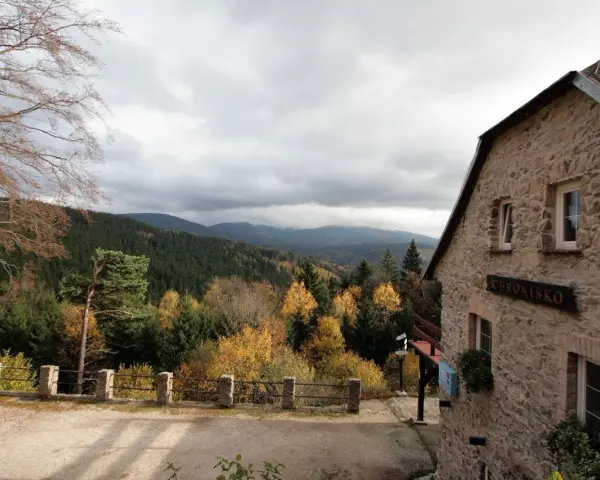 Kamienny budynek schroniska na Iglicznej z widokiem na jesienne góry.