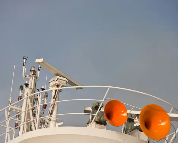 Zwei orangefarbene Schiffshörner sind bereit, ihr Signal zu geben. Das Schiff hupt 3 mal lang, um seine Anwesenheit zu signalisieren.