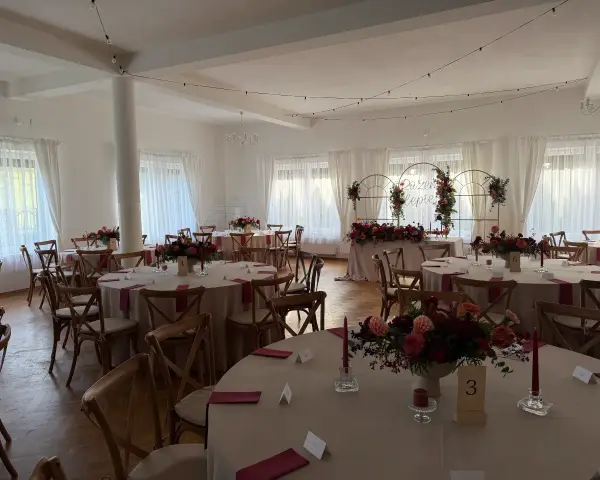 Elegancka sala weselna z okrągłymi stołami, kwiatami i świecami. Idealne miejsce, by wybrać najlepszą salę na wesele.