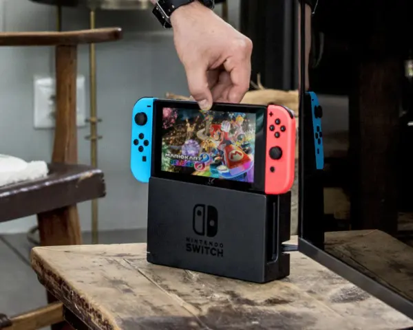 Mano insertando la Nintendo Switch en su base, lista para jugar Mario Kart 8 Deluxe, uno de los mejores juegos estrategia switch.
