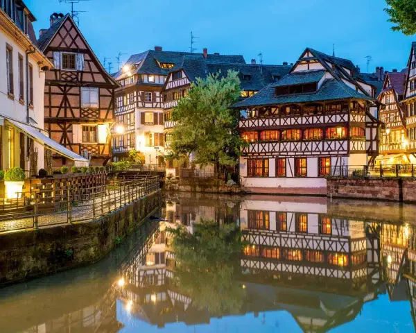 Casas con entramado de madera reflejadas en un canal, un ejemplo de la calidad de vida en Francia.