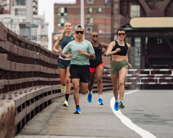 Grupa biegaczy w różnym tempie pokonuje trasę. Intensywny fartlek run na moście miejskim.