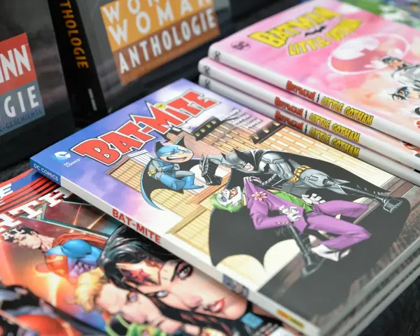 Fumetti DC Comics impilati, tra cui "Bat-Mite" e "Batman Little Gotham". Un lavoro da fumettista che prende vita.