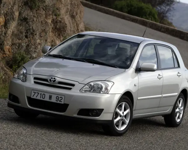 Srebrna Toyota Corolla E12 na krętej drodze, z kamienistym zboczem w tle.