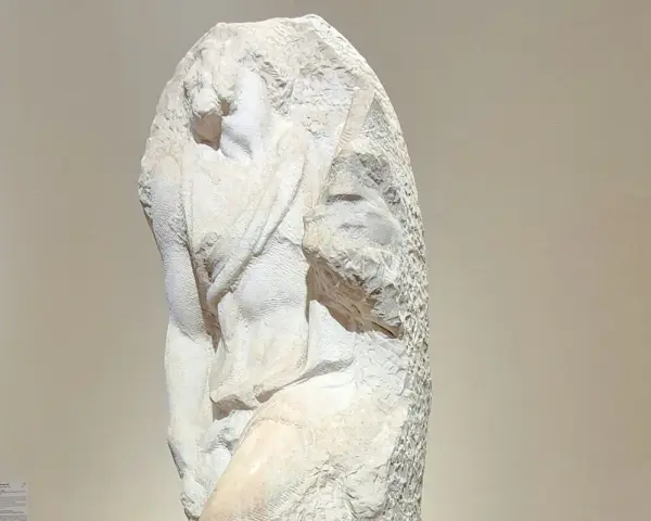Niedokończony posąg Michała Anioła, ukazujący fragment ludzkiego ciała wyrzeźbionego z marmuru.