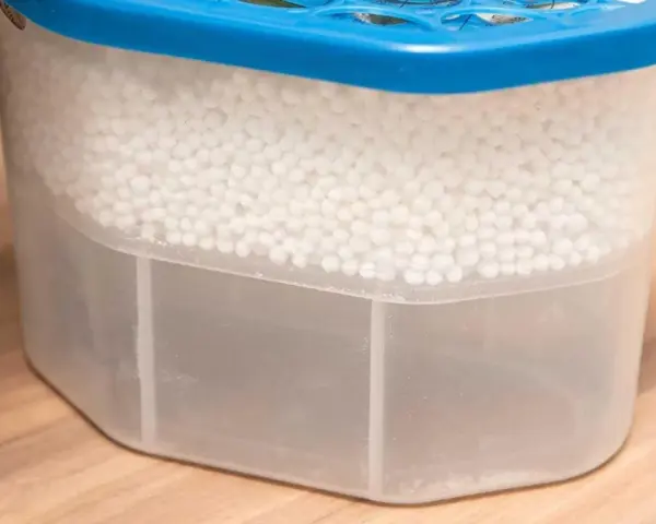 Luftentfeuchter Granulat wird hart, wenn es Feuchtigkeit aufnimmt. Der Behälter zeigt, wie das Granulat die Luft trocknet und sich unten Wasser sammelt.