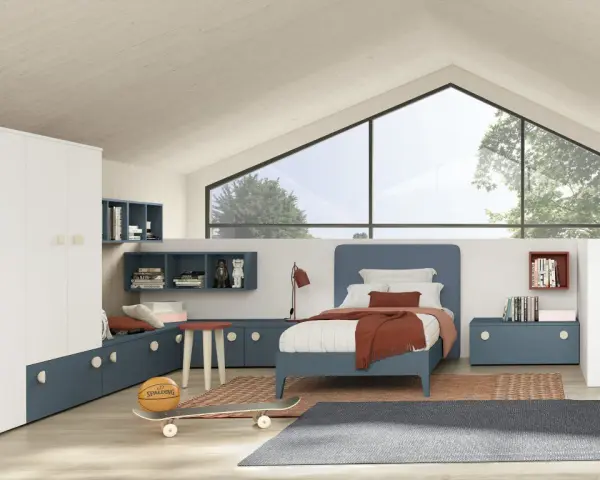 Un accogliente **letto sotto la finestra** in una stanza moderna, con armadio bianco, librerie blu e un pallone da basket.