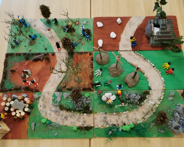 Kinder gestalten einen Kreuzweg mit Spielfiguren und Naturmaterialien. Kleine Szenen zeigen Stationen des Leidenswegs.