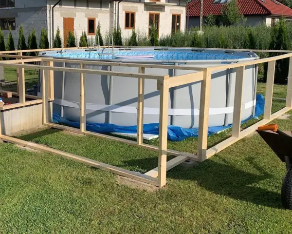 Drewniana konstrukcja wokół basenu ogrodowego w trakcie budowy.