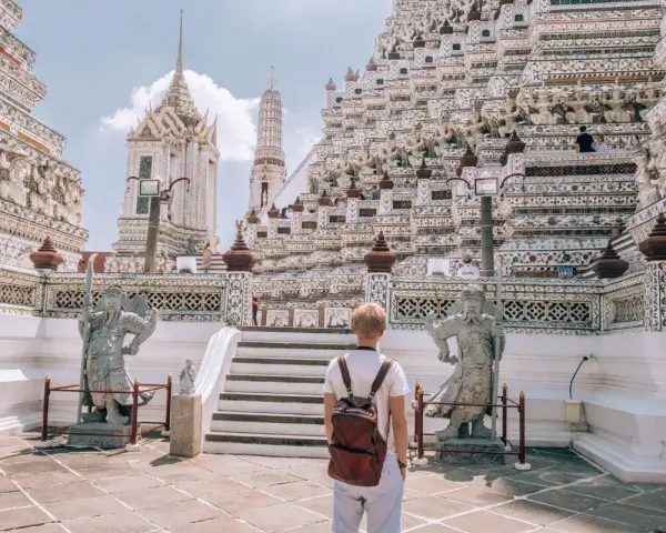 Młody turysta z plecakiem podziwia majestatyczną świątynię Wat Arun w Bangkoku. Czy Bangkok jest bezpieczny? Tak, zwłaszcza w takich pięknych i spokojnych miejscach.