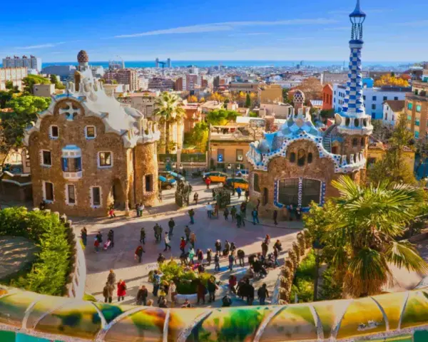 A vibrant view of Park Güell in Barcelona, with its iconic mosaic-covered benches and whimsical buildings. This is the perfect place to start your trein naar Barcelona adventure.